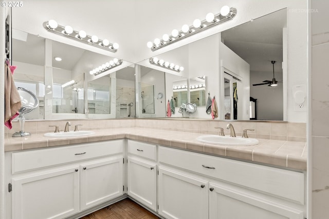 full bathroom with double vanity, a ceiling fan, a sink, and a shower with shower door