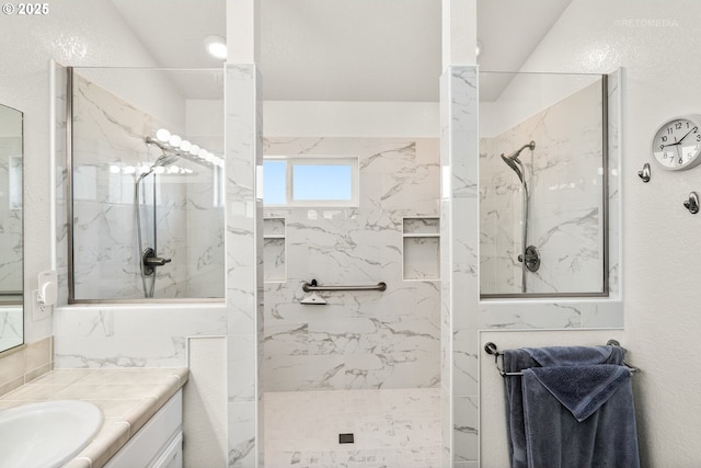 full bath with a marble finish shower and vanity