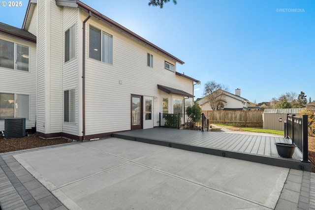 rear view of property featuring a deck, an outbuilding, cooling unit, fence, and a shed