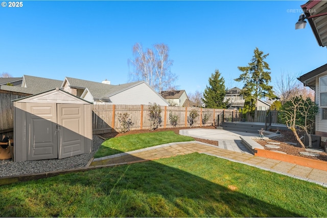 view of yard featuring an outbuilding, a patio, a storage shed, and a fenced backyard