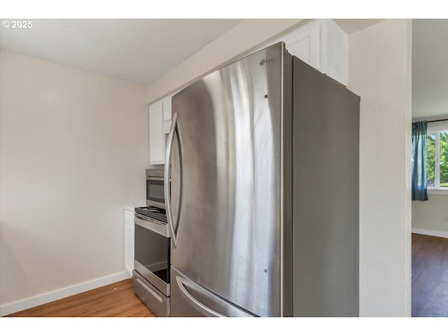 kitchen featuring baseboards, light wood-style flooring, white cabinetry, and stainless steel appliances