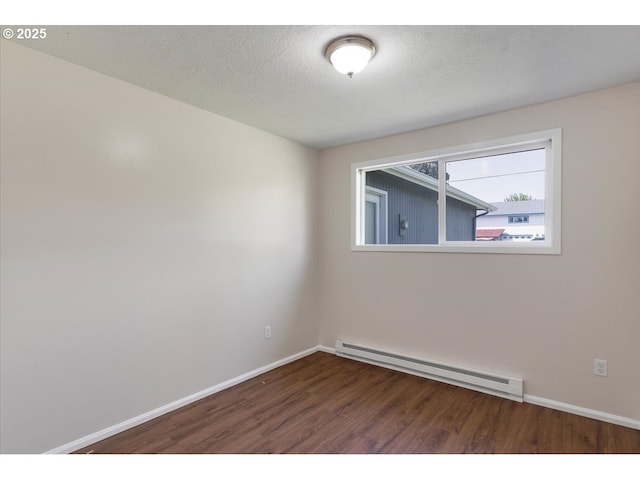 empty room with wood finished floors, baseboards, and a baseboard heating unit