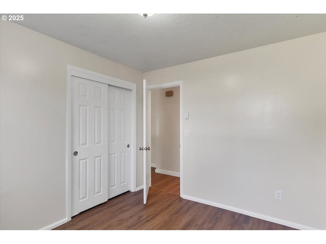unfurnished bedroom with baseboards, wood finished floors, and a closet