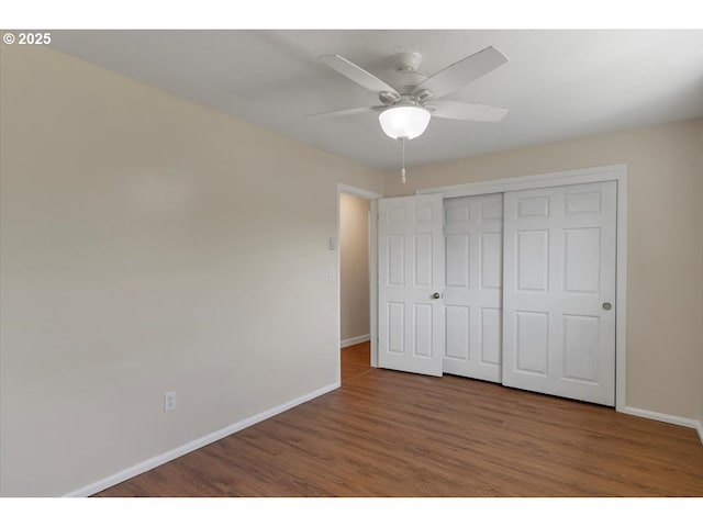 unfurnished bedroom featuring baseboards, ceiling fan, a closet, and wood finished floors