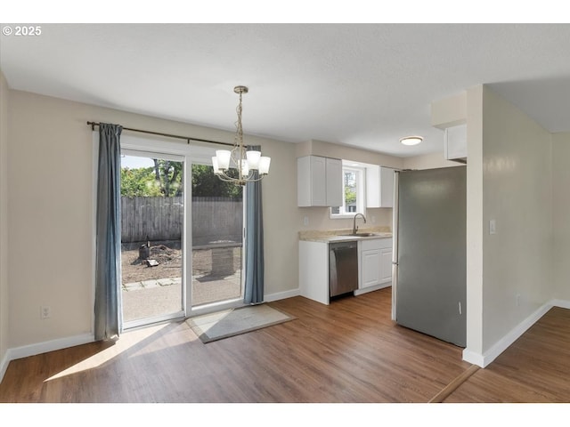 kitchen featuring light countertops, baseboards, white cabinets, a notable chandelier, and stainless steel appliances