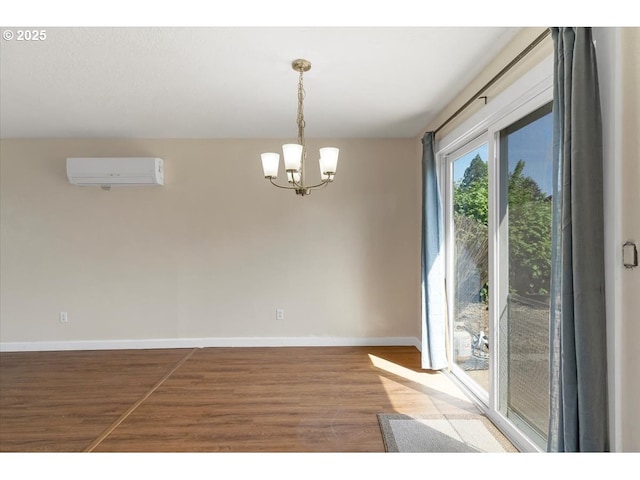 unfurnished dining area with an AC wall unit, baseboards, wood finished floors, and a notable chandelier