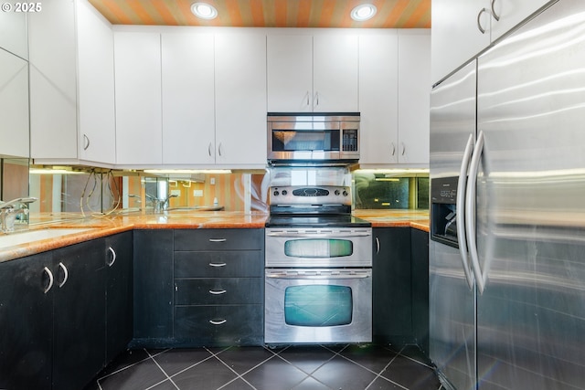kitchen featuring appliances with stainless steel finishes, dark tile patterned flooring, a sink, light countertops, and recessed lighting