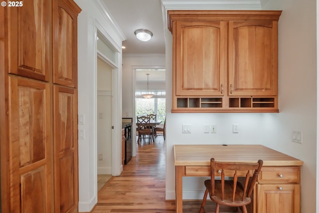 hall with baseboards, ornamental molding, and light wood finished floors