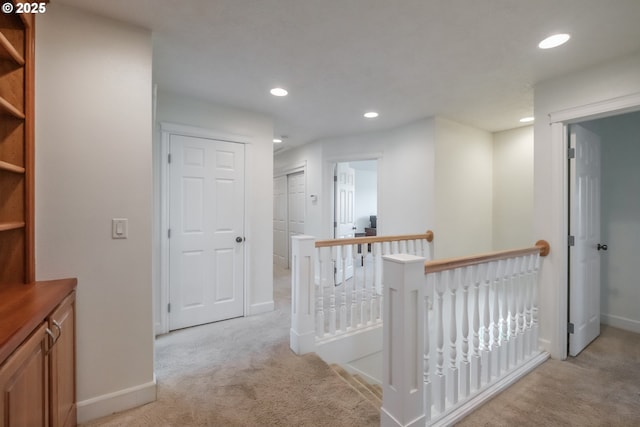 hall with recessed lighting, baseboards, an upstairs landing, and light carpet