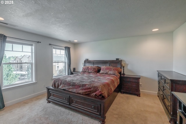 bedroom featuring baseboards, visible vents, a textured ceiling, and light colored carpet