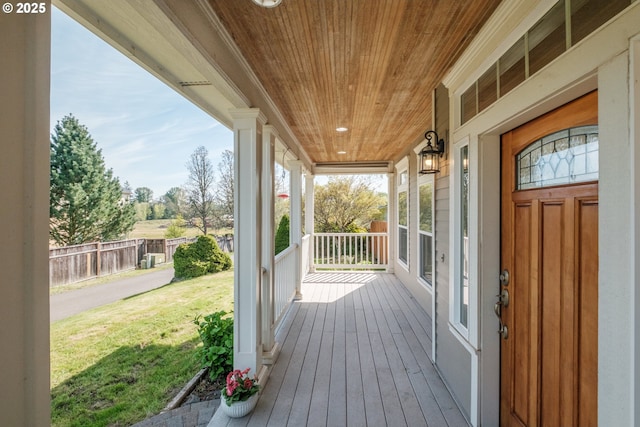 wooden deck featuring covered porch, a yard, and fence