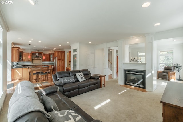 living area with recessed lighting, a multi sided fireplace, ornate columns, and light carpet