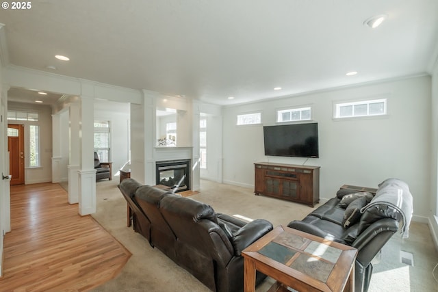 living room featuring crown molding, a multi sided fireplace, recessed lighting, baseboards, and ornate columns