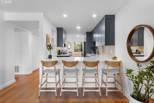 kitchen with a sink, tasteful backsplash, visible vents, stove, and light countertops