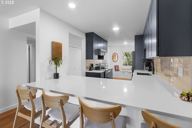 kitchen featuring recessed lighting, tasteful backsplash, stainless steel electric range oven, and a sink
