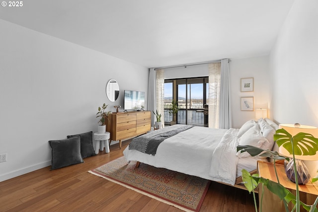 bedroom with baseboards, access to outside, and wood finished floors
