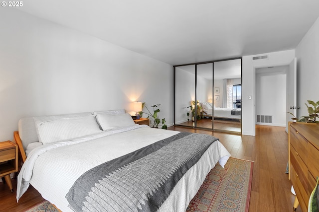 bedroom with baseboards, hardwood / wood-style floors, and visible vents