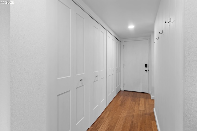corridor with baseboards, wood finished floors, and recessed lighting