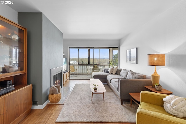 living area with light wood-style flooring, baseboards, and a fireplace