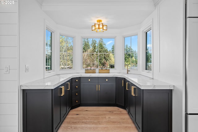 bar with light wood-style floors, a chandelier, and built in refrigerator