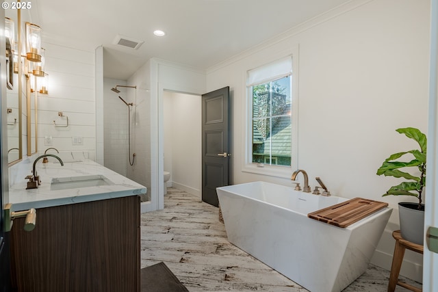 full bathroom featuring ornamental molding, toilet, a shower stall, double vanity, and a soaking tub