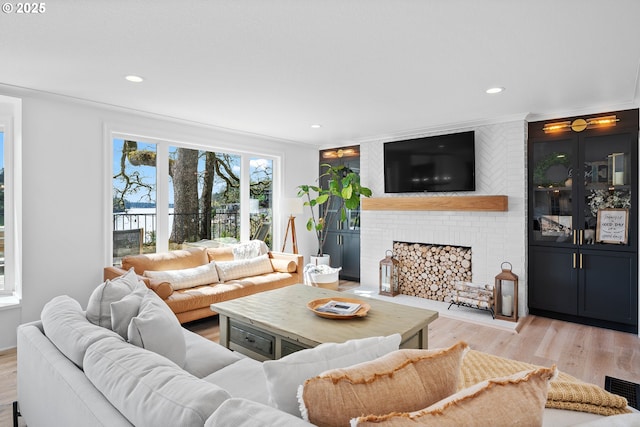 living room with light wood finished floors, recessed lighting, and a brick fireplace