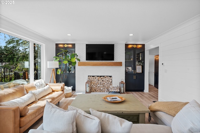living room featuring ornamental molding, light wood-type flooring, a fireplace, and recessed lighting