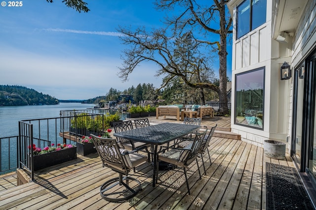 wooden deck with a water view, outdoor dining space, and outdoor lounge area