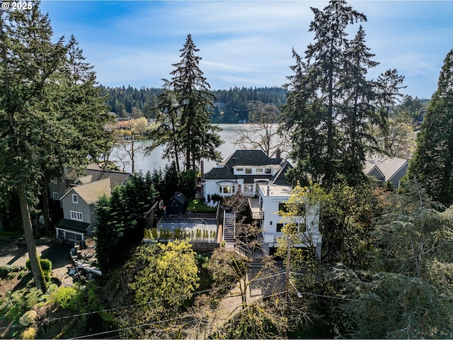 view from above of property with a heavily wooded area and a nearby body of water