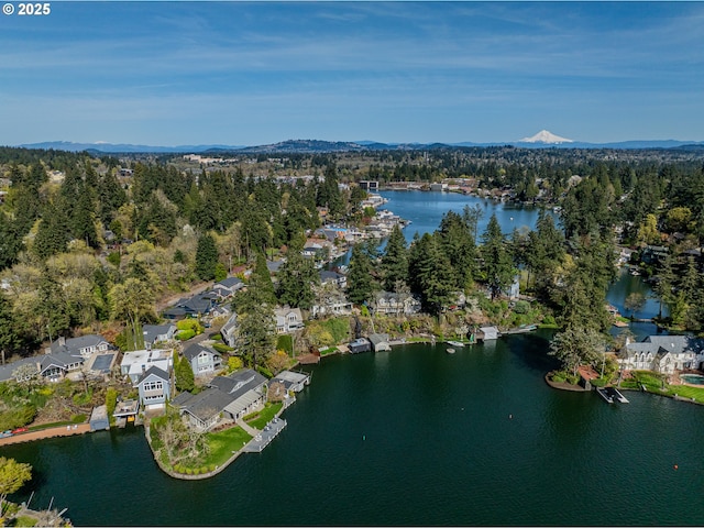 aerial view of property and surrounding area with a water and mountain view, nearby suburban area, and a heavily wooded area