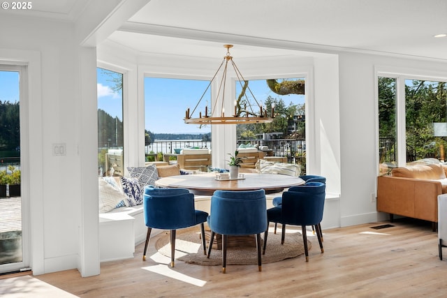 dining area with plenty of natural light, wood finished floors, a chandelier, ornamental molding, and baseboards