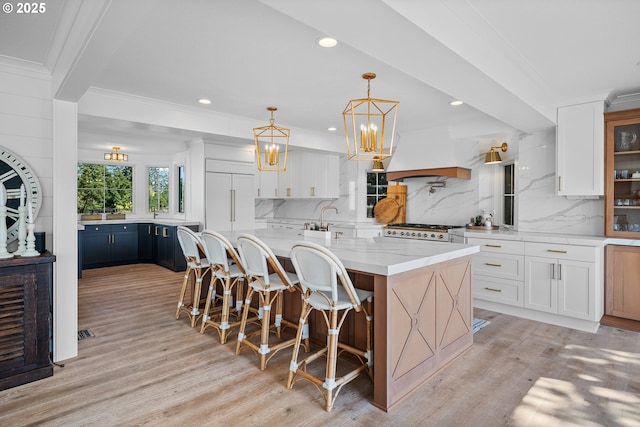 kitchen featuring light wood-style floors, stove, backsplash, white cabinets, and crown molding