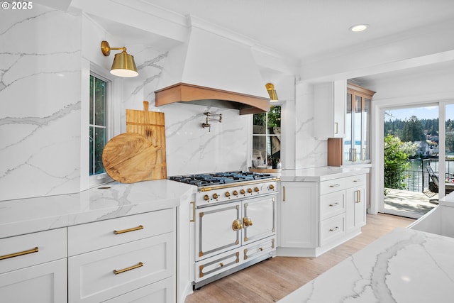 kitchen featuring range with two ovens, custom range hood, tasteful backsplash, light stone counters, and white cabinets