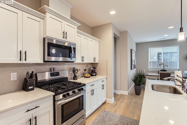 kitchen with pendant lighting, stainless steel appliances, light stone countertops, and white cabinets