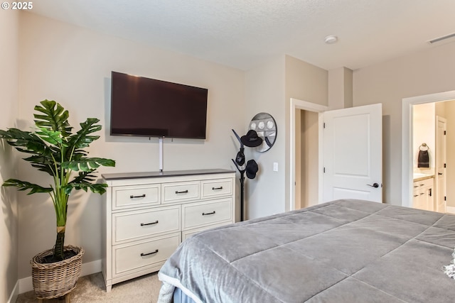 bedroom with light colored carpet and ensuite bathroom