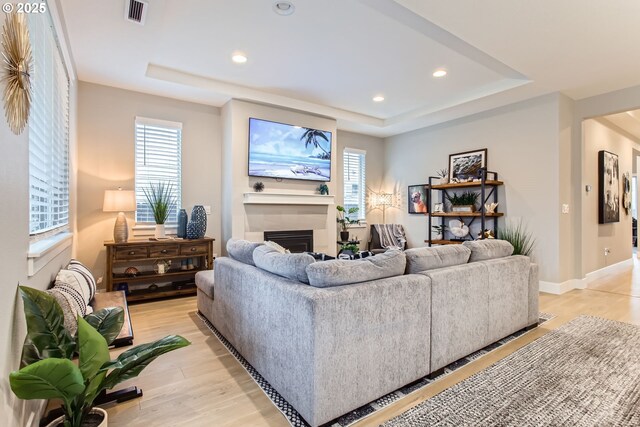 living room with a tray ceiling and light hardwood / wood-style floors