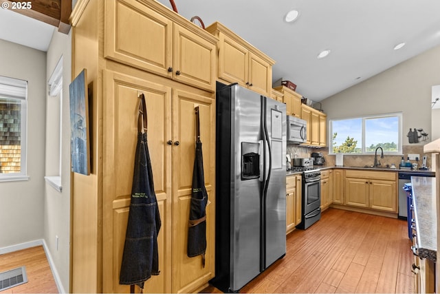 238 SW 27th St, Newport, OR 97365 - kitchen with stainless steel appliances, light brown cabinets, a sink, light wood-style flooring, and decorative backsplash