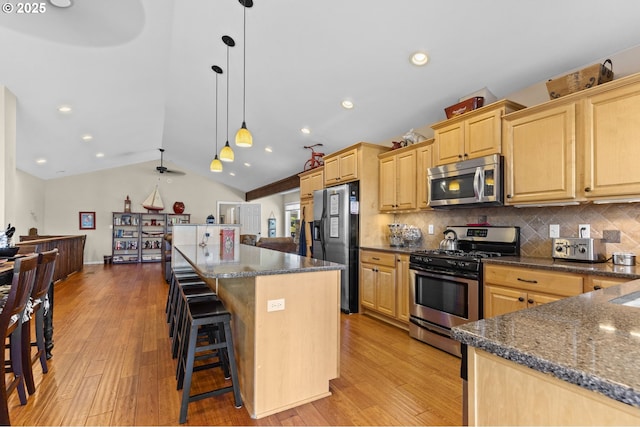 238 SW 27th St, Newport, OR 97365 - kitchen featuring appliances with stainless steel finishes, a center island, light brown cabinetry, light wood-style flooring, and lofted ceiling