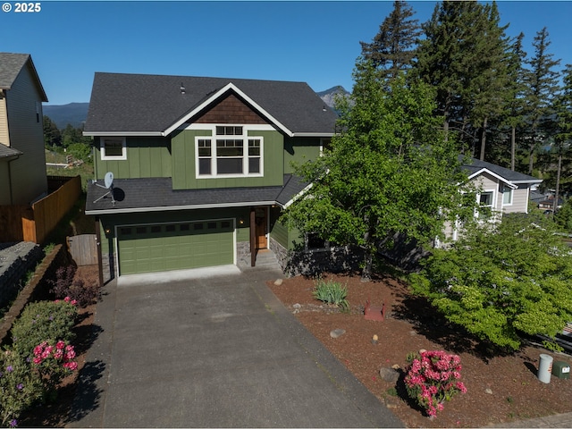 craftsman house with fence, an attached garage, stone siding, driveway, and board and batten siding