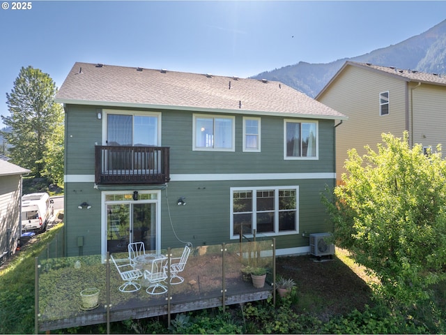 back of property with a balcony, a deck with mountain view, and ac unit