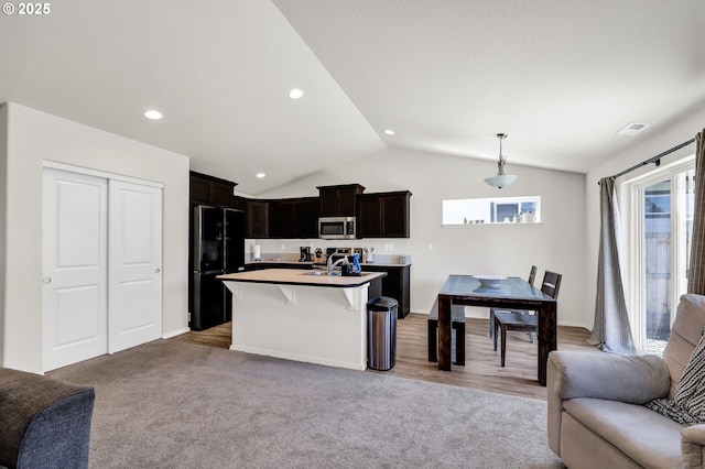 717 S 53rd Pl, Springfield, OR 97478 - kitchen featuring open floor plan, stainless steel microwave, freestanding refrigerator, lofted ceiling, and a kitchen island with sink