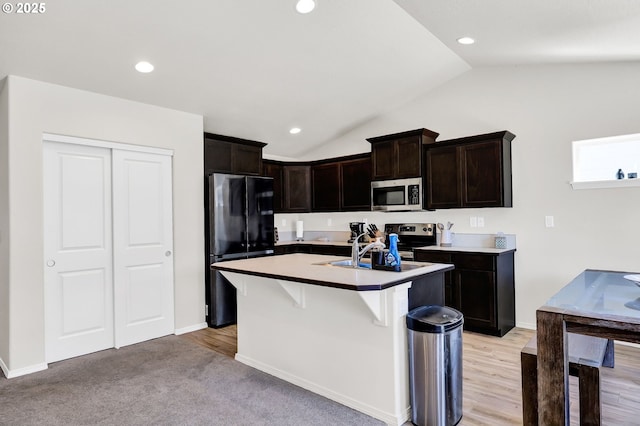 717 S 53rd Pl, Springfield, OR 97478 - kitchen with appliances with stainless steel finishes, lofted ceiling, a kitchen island with sink, a breakfast bar area, and dark brown cabinets