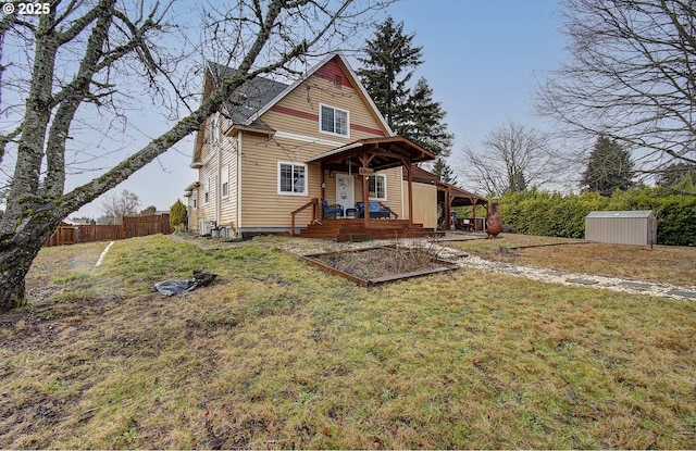 back of house featuring a storage shed, covered porch, and a lawn