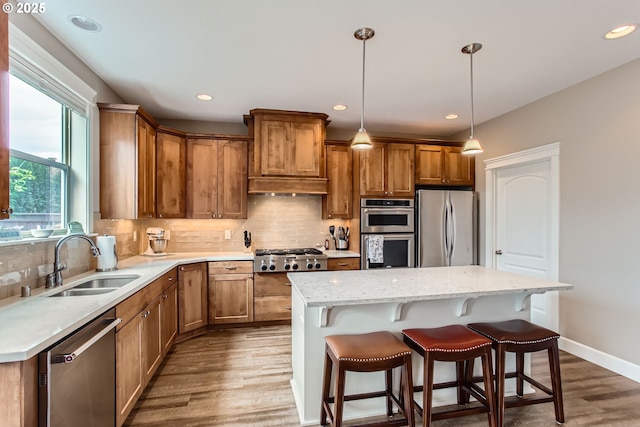 kitchen with appliances with stainless steel finishes, a sink, dark wood-style flooring, a breakfast bar area, and tasteful backsplash
