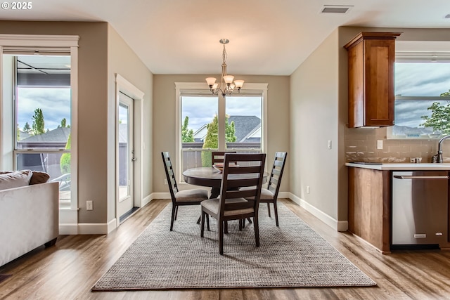 dining space with a chandelier, light wood-type flooring, and baseboards