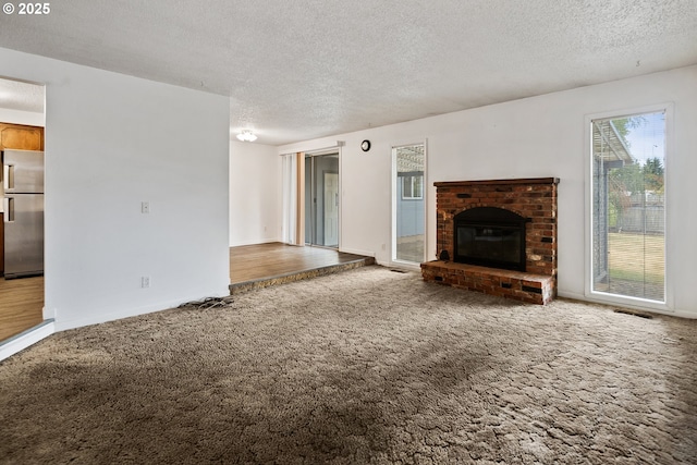 11613 Pacific Ct NE, Woodburn, OR 97071 - unfurnished living room featuring a textured ceiling, carpet flooring, and a fireplace