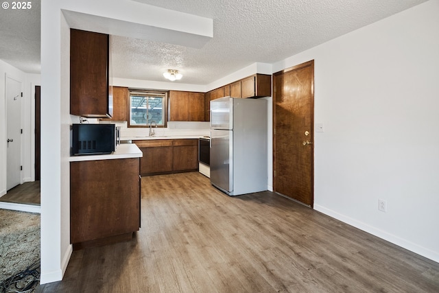 11613 Pacific Ct NE, Woodburn, OR 97071 - kitchen with freestanding refrigerator, black microwave, light wood-style flooring, and a textured ceiling