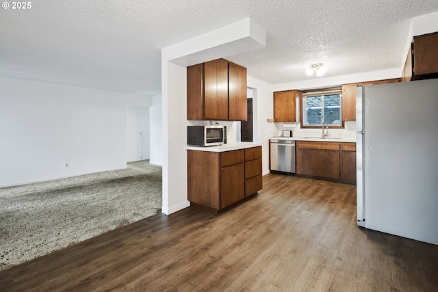 11613 Pacific Ct NE, Woodburn, OR 97071 - kitchen featuring stainless steel appliances, dark wood-style flooring, light countertops, brown cabinets, and a textured ceiling