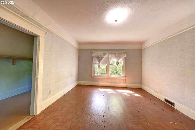 empty room featuring visible vents, baseboards, and a textured ceiling