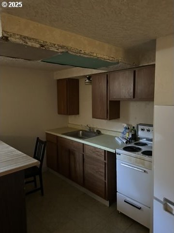 kitchen with electric stove, a sink, and light countertops